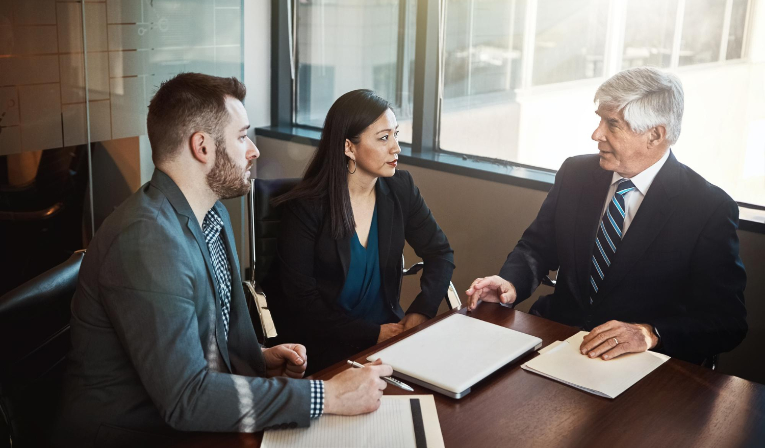 Business owners and attorney negotiating the purchase and sale of a company during a business acquisition transaction.